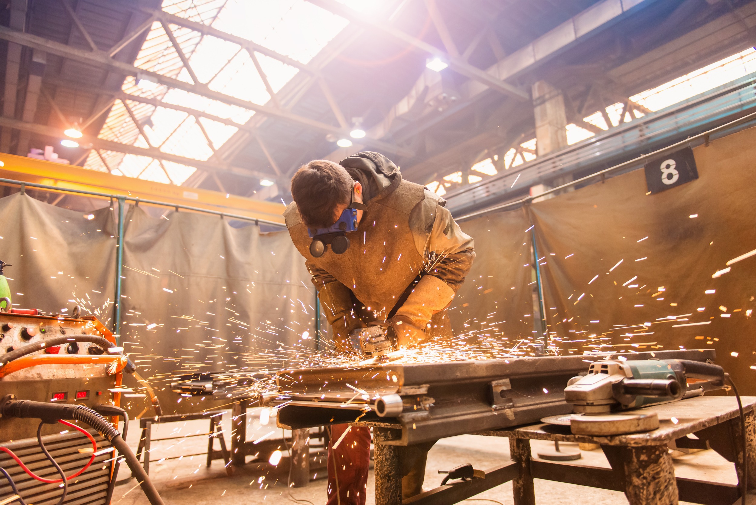 Young man with protective goggles welding in a factory